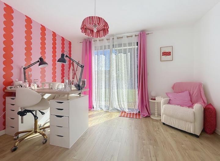 Le mur festonné rose et rouge du salon, avec le bureau de pose et le fauteuil d'attente